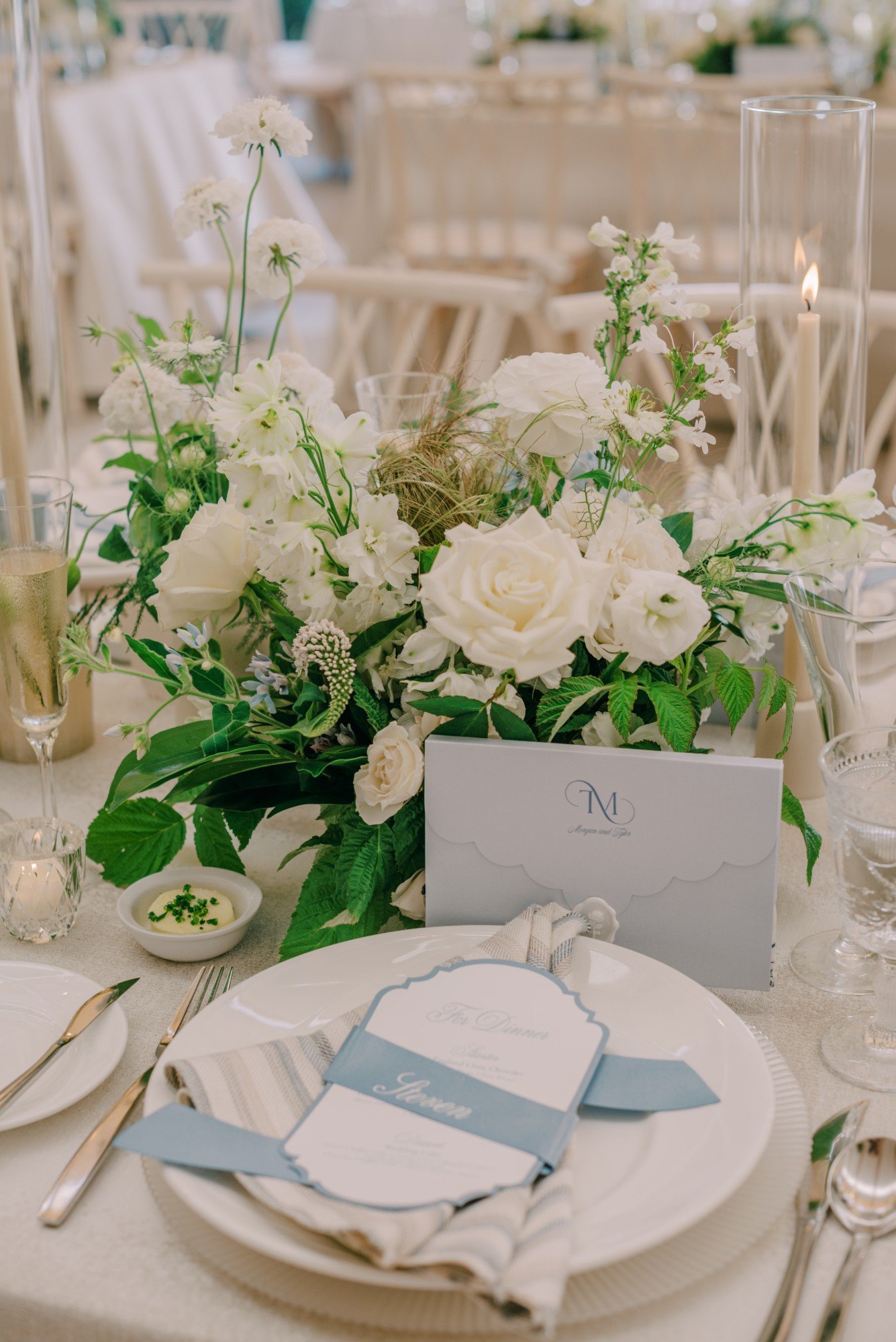 A scarf display envelope tucked into a white-and-green wedding centerpiece at a styled reception table